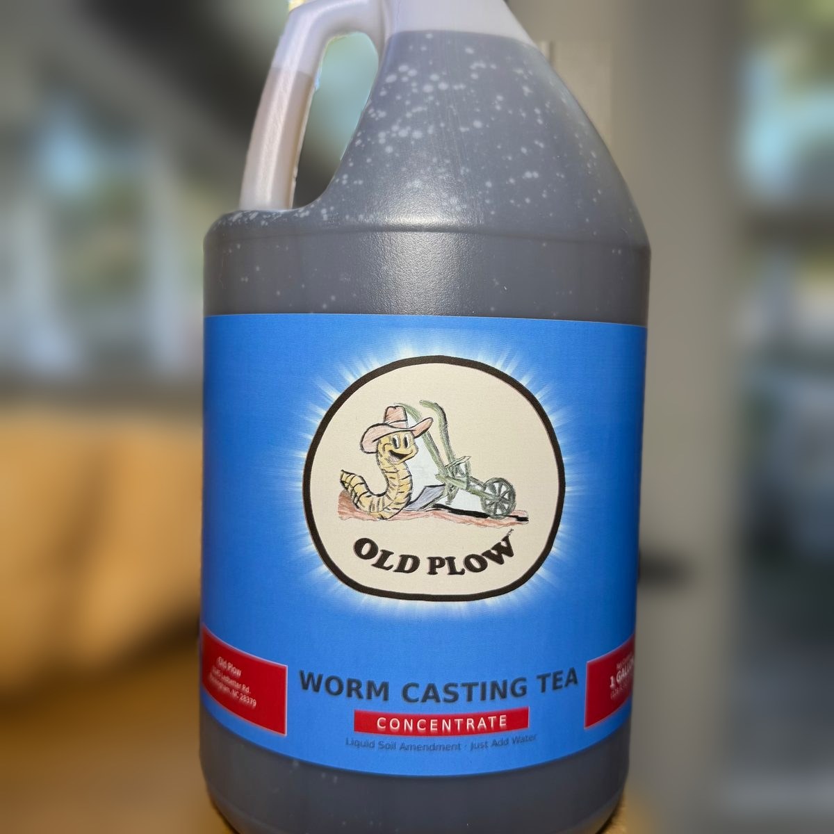 Gallon jug of Old Plow Worm Casting Tea concentrate on a porch table
